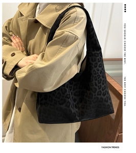 Detail of black leopard print tote bag paired with a classic khaki trench coat
