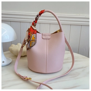 Detail of pink lychee leather bucket bag featuring a silk scarf handle and golden hardware