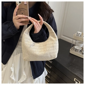 Détail d'un sac à main croissant en paille beige avec motif de tissage en V élégant