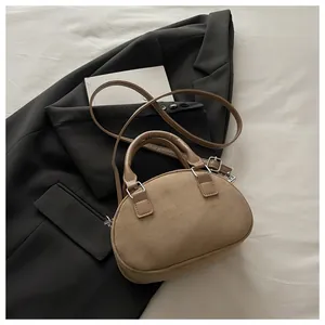 Detail of camel suede semi-circle handbag on black blazer with silver metal clasp