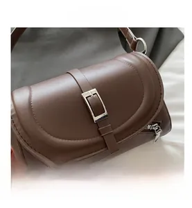 Detail view of dark brown leather handbag with silver metal buckle and side zipper