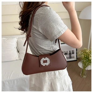 Close-up of a dark brown leather baguette bag with a sparkling crystal square buckle