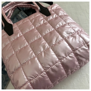 Detail of pink quilted tote bag showing shiny metallic finish and black handle accents