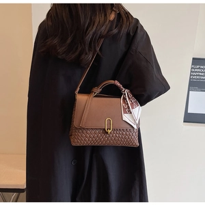 Detailed view of a brown woven leather crossbody bag with decorative silk scarf handle