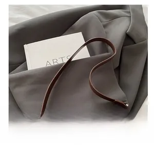 Detail showing the brown leather handbag with silver magnetic closure and round handle