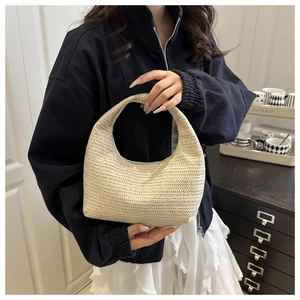 Detail of hand-woven straw hobo bag with beige herringbone texture in a lifestyle setting