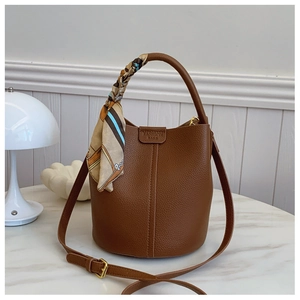 Detailed close-up of brown litchi grain leather bucket bag with decorative floral scarf handle