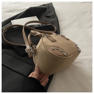 Detail view of khaki suede Boston bag with silver rivets on dark blazer background