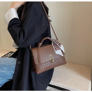 Detail of a brown woven leather handbag featuring a silk scarf handle and gold buckle