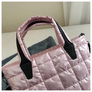 Detail of pink quilted puffer bag showing glossy texture and black leather handles