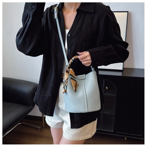 Detail of light blue lychee pattern bucket bag with silk scarf and leather shoulder strap