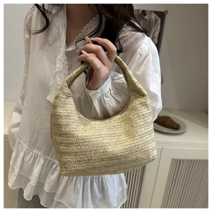 Detail of woven straw crescent handbag with natural fiber texture and integrated handle