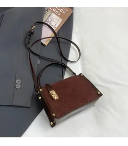 Detailed view of brown suede crossbody bag with diamond quilting and gold buckle