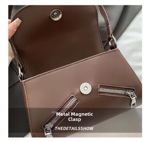 Macro shot of magnetic closure and metallic zipper detail on brown leather baguette bag