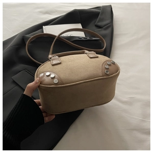 Detail of tan suede trapezoid handbag featuring silver studs and leather shoulder strap