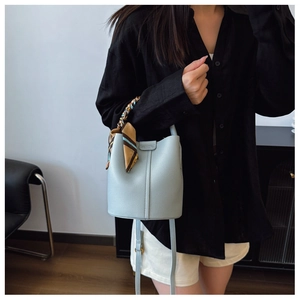 Detail of light blue lychee pattern leather bucket bag with decorative silk scarf handle