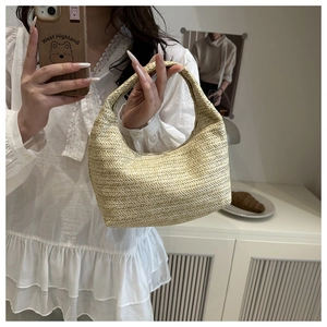 Gros plan du sac à main tressé beige montrant le motif chevrons et sa forme en demi-lune