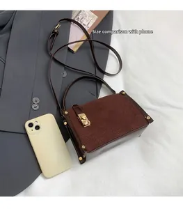 Brown suede crossbody bag size comparison with mobile phone for scale and dimensions