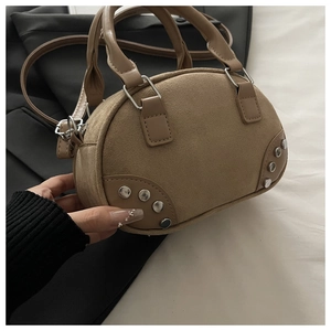 Detail of rivet-studded corners on a khaki faux suede mini bowling bag with leather accents