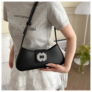 Detail of a black leather baguette bag featuring a luxury square rhinestone buckle design