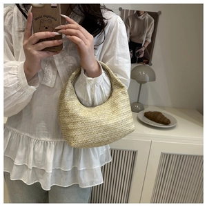 Détail du sac à main beige tressé en forme de croissant dans un décor intérieur de style vie