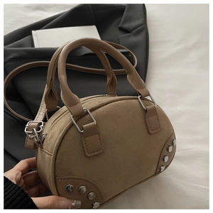 Detail of khaki suede pillow bag showing silver rivets and cylindrical dual handles