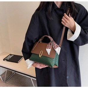 Detail of a two-tone crossbody bag featuring green woven texture and scarf-wrapped handle