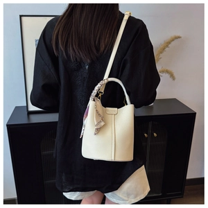 Detail of cream lychee leather bucket bag with silk scarf and gold fashion logo