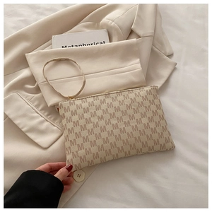 Detail of minimalist beige envelope bag with all-over M pattern and wrist strap