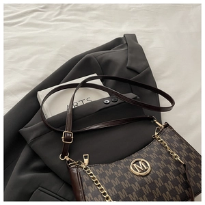 Dettaglio borsa a mezzaluna in tela monogram con catena dorata su un blazer