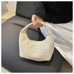 Detailed view of the ivory woven straw handbag with a minimalist herringbone texture pattern