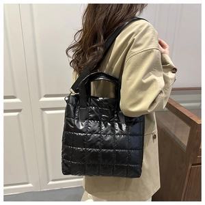 Detail of black quilted puffer tote bag with glossy finish and detachable shoulder strap