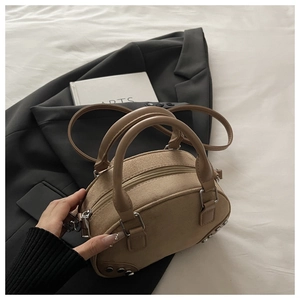 Detail of khaki suede mini pillow bag with silver rivets and sleek curved top handles