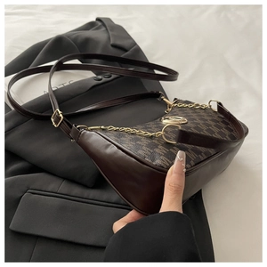 Dettaglio borsa a mezzaluna marrone con stampa monogramma e logo in metallo oro