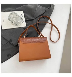 Nahaufnahme der karamellbraunen Handtasche mit Krokostruktur und goldenen Metallfüßen