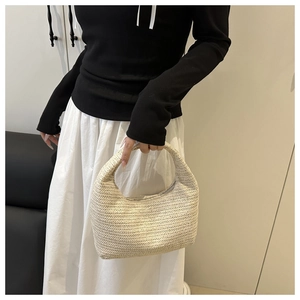 Detailed close-up of straw woven hobo bag with beige herringbone texture and hand strap