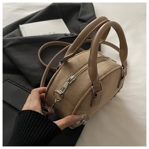 Close-up of retro boston bag in beige suede with metal rivets and sturdy dual handles