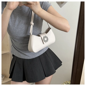 Mirror selfie showing a cream baguette shoulder bag with a crystal buckle decoration