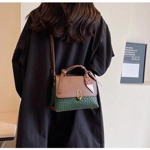 Detail of bicolored crossbody bag featuring faux snakeskin texture and silk scarf handle