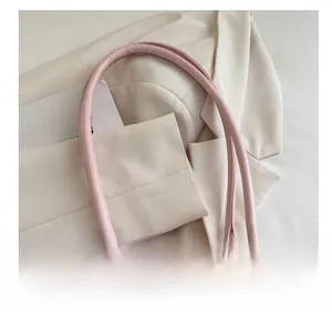 Detail of light pink leather double handles with gold D-ring hardware and neat stitching