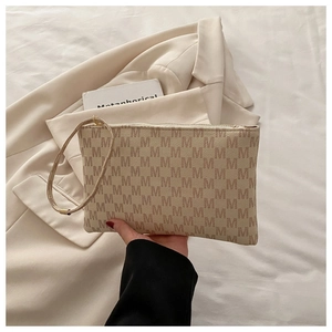 Detail of minimalist envelope clutch with brown M-pattern monogram and leather wristlet strap