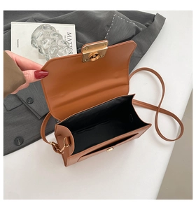 Draufsicht auf offene braune Ledertasche mit Innenraum und goldenem Metallverschluss