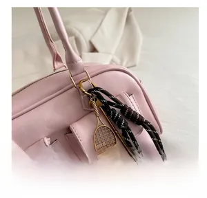 Close-up of pink faux leather handbag featuring dual pockets and tennis racket pendant