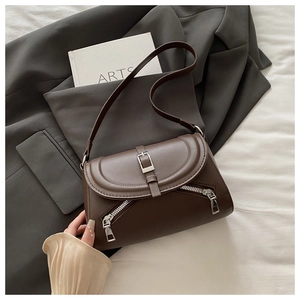 Detail of dark brown leather underarm bag featuring silver buckle and dual zipper accents
