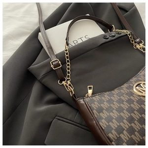 Dettaglio borsa a mezzaluna marrone monogramma con logo M dorato e tracolla a catena