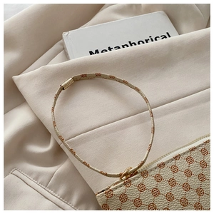 Detail of cream envelope bag with red clover pattern and light gold metal zipper closure