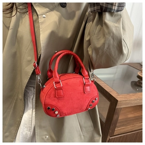 Detailed shot of red suede crossbody bag with silver rivet studs on beige coat