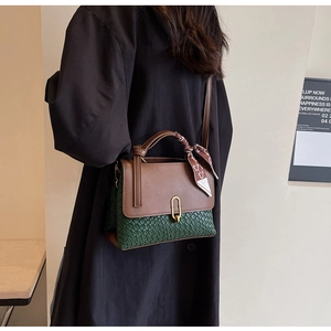 Detail of green woven handbag with brown leather flap and silk scarf on handle