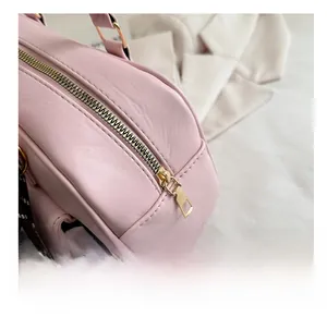 Detailed close-up of the smooth gold-toned metal zipper on a pink leather handbag