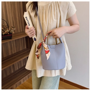 Detail of lychee pattern leather bucket bag with decorative floral silk scarf handle